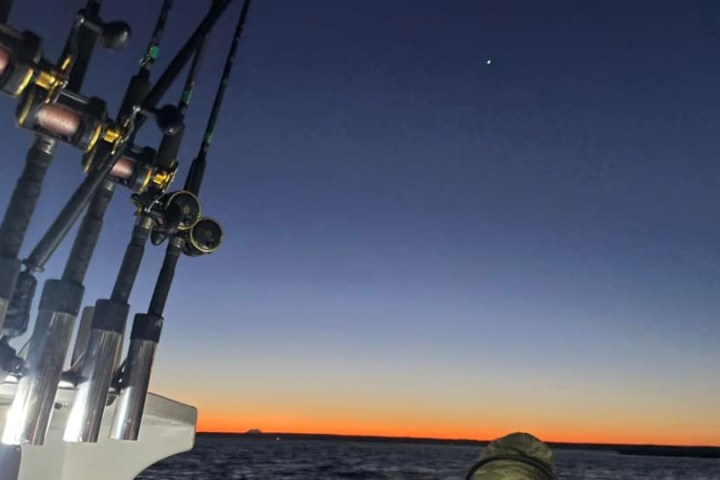 Rods on a boat at sunset with a clear sky and a star visible.