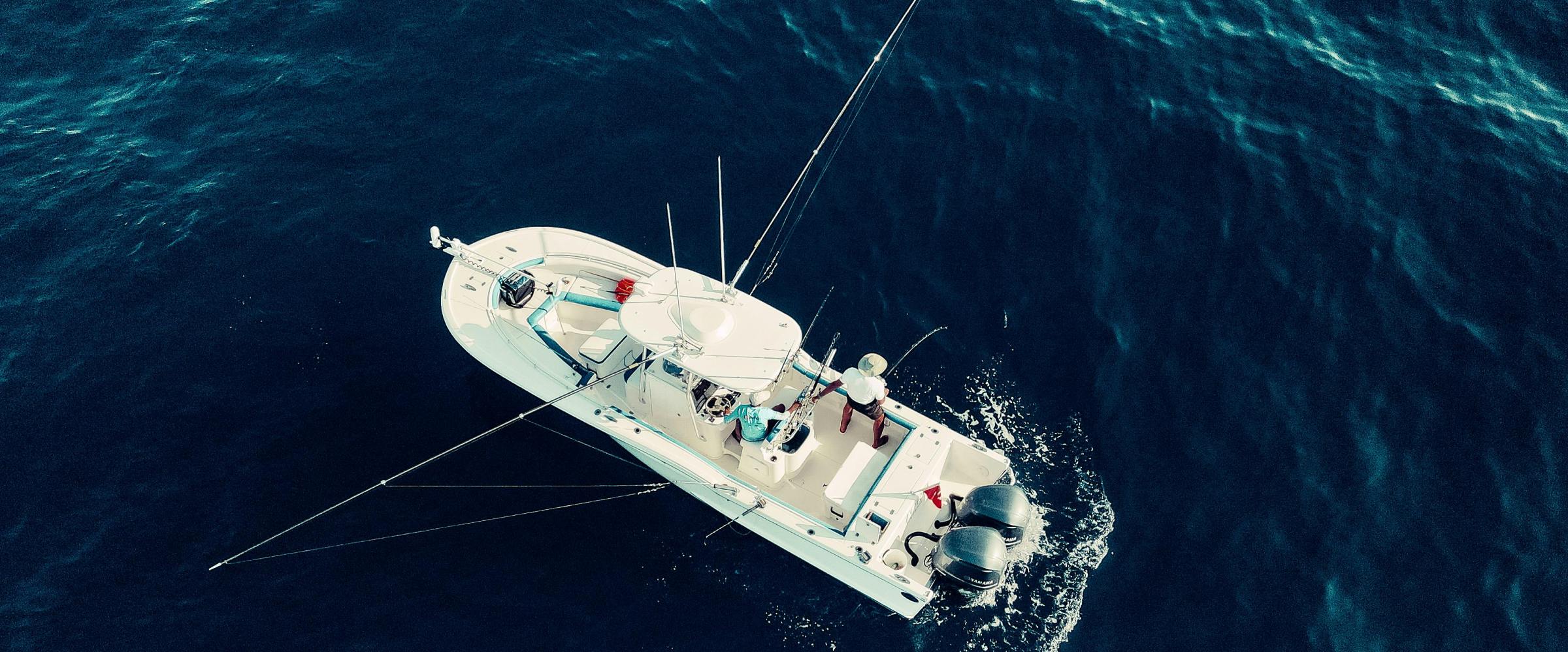 Aerial view of a small motorboat with fishing rods in open blue water.